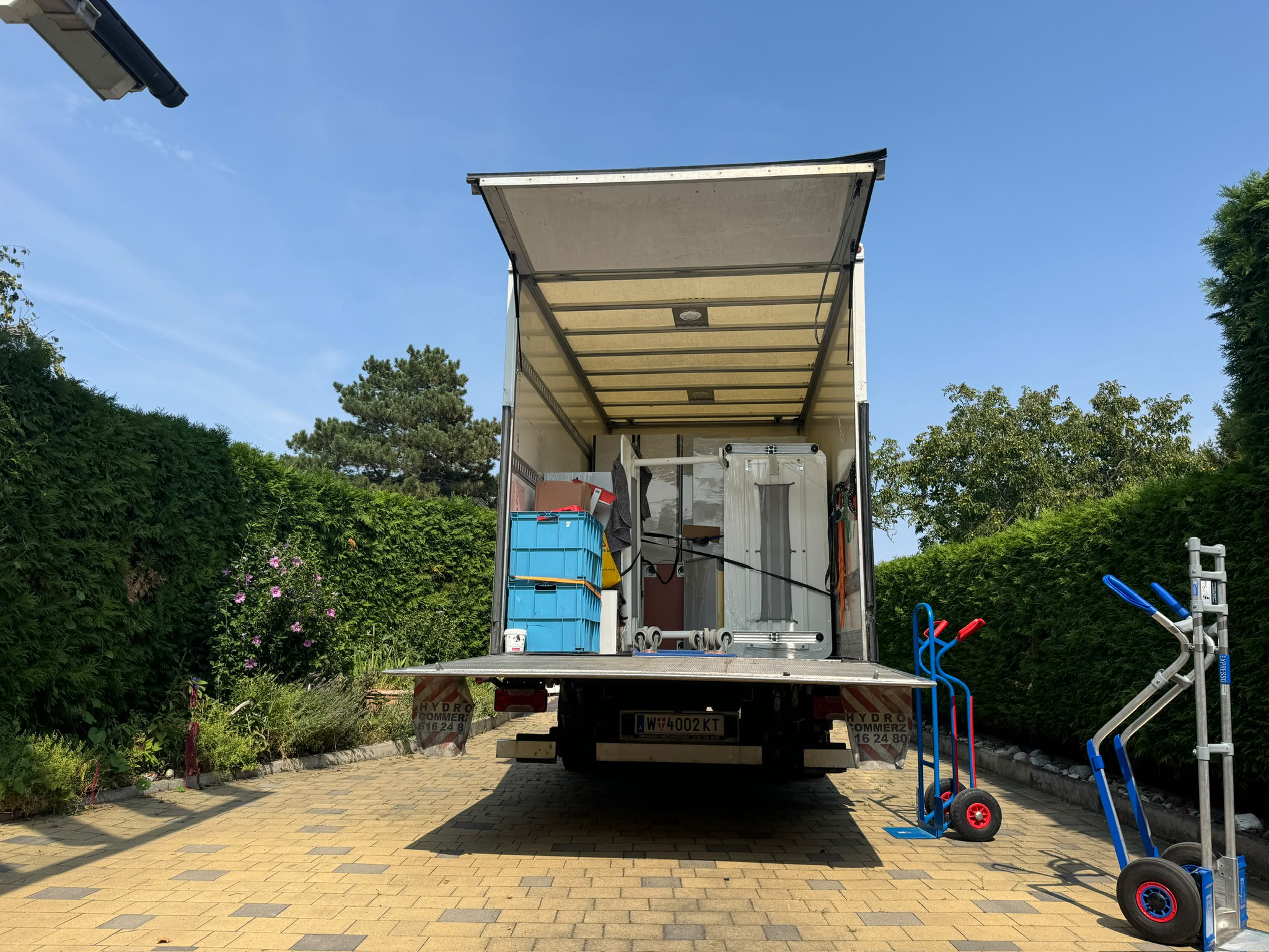LKW mit Hebebühne vor einem Einfamilienhaus mit Garten